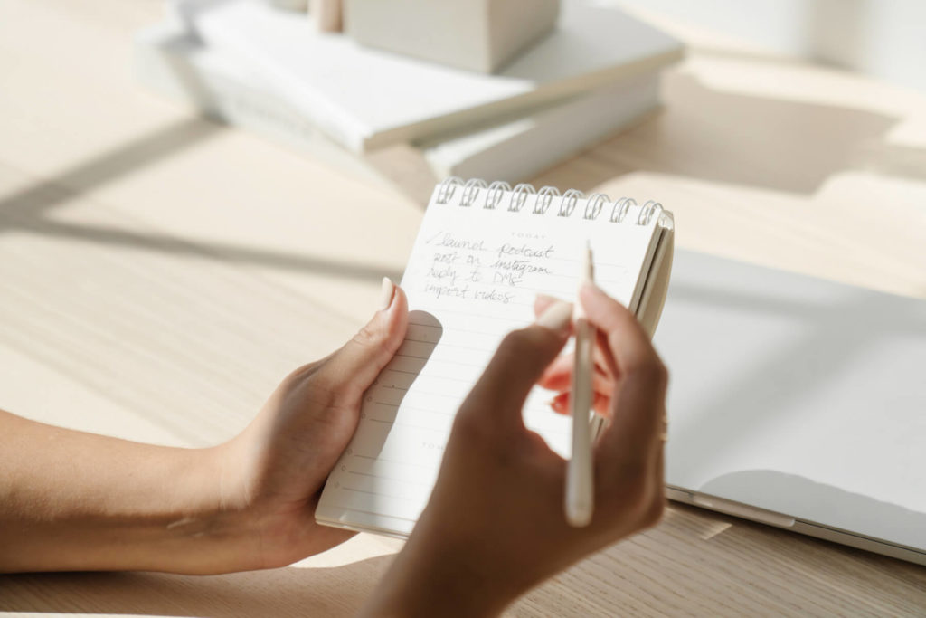 woman writing a list of to-do's in a notebook to audit her website 