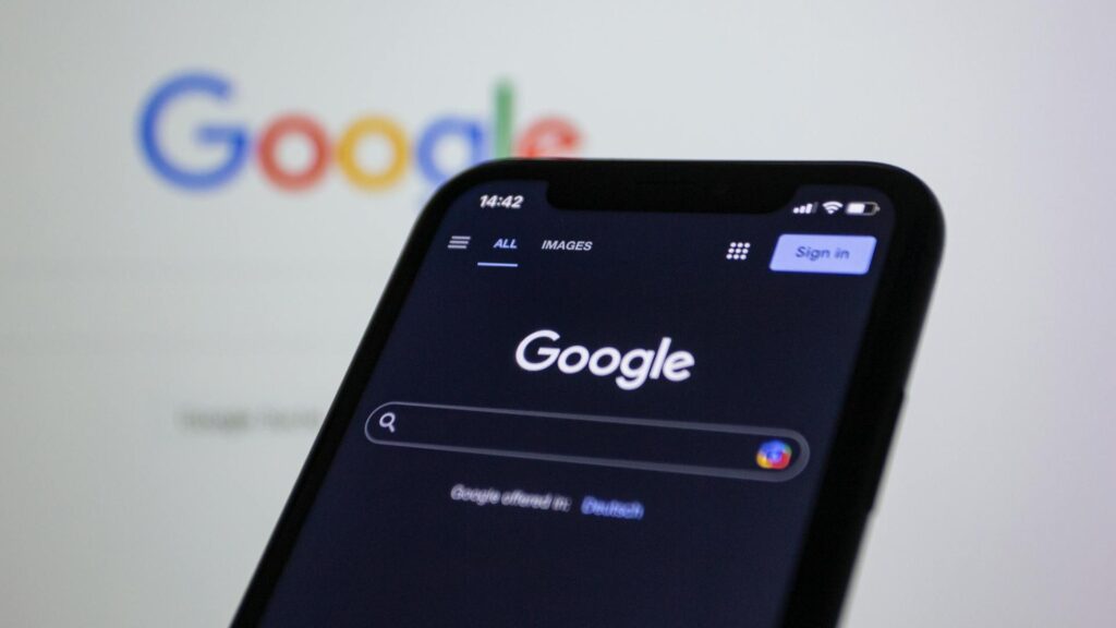 google search on a mobile phone with google search on a computer in the background