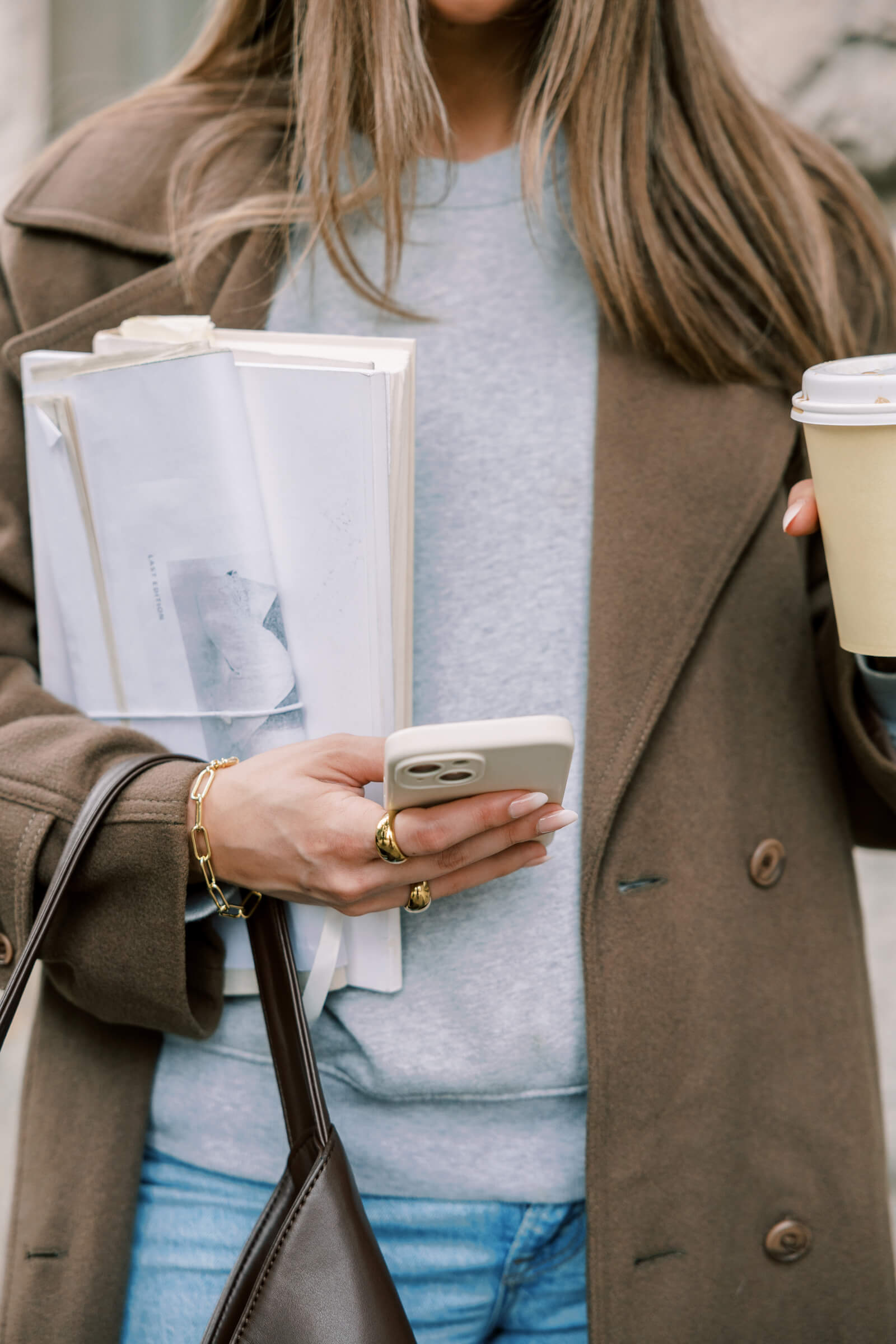 business woman holding a coffee and checking her phone