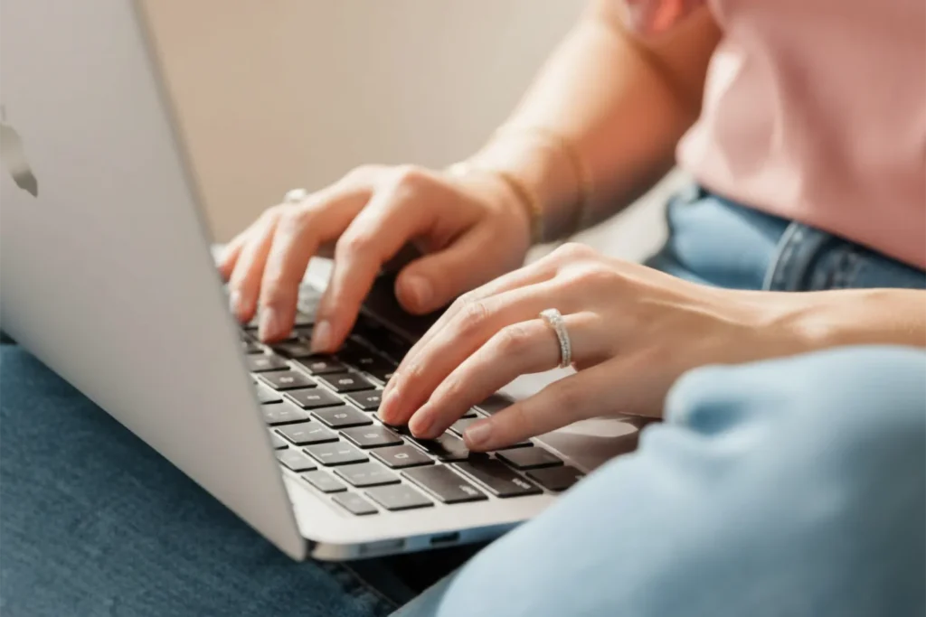 closeup of woman typing a blog on a laptop apple computer
