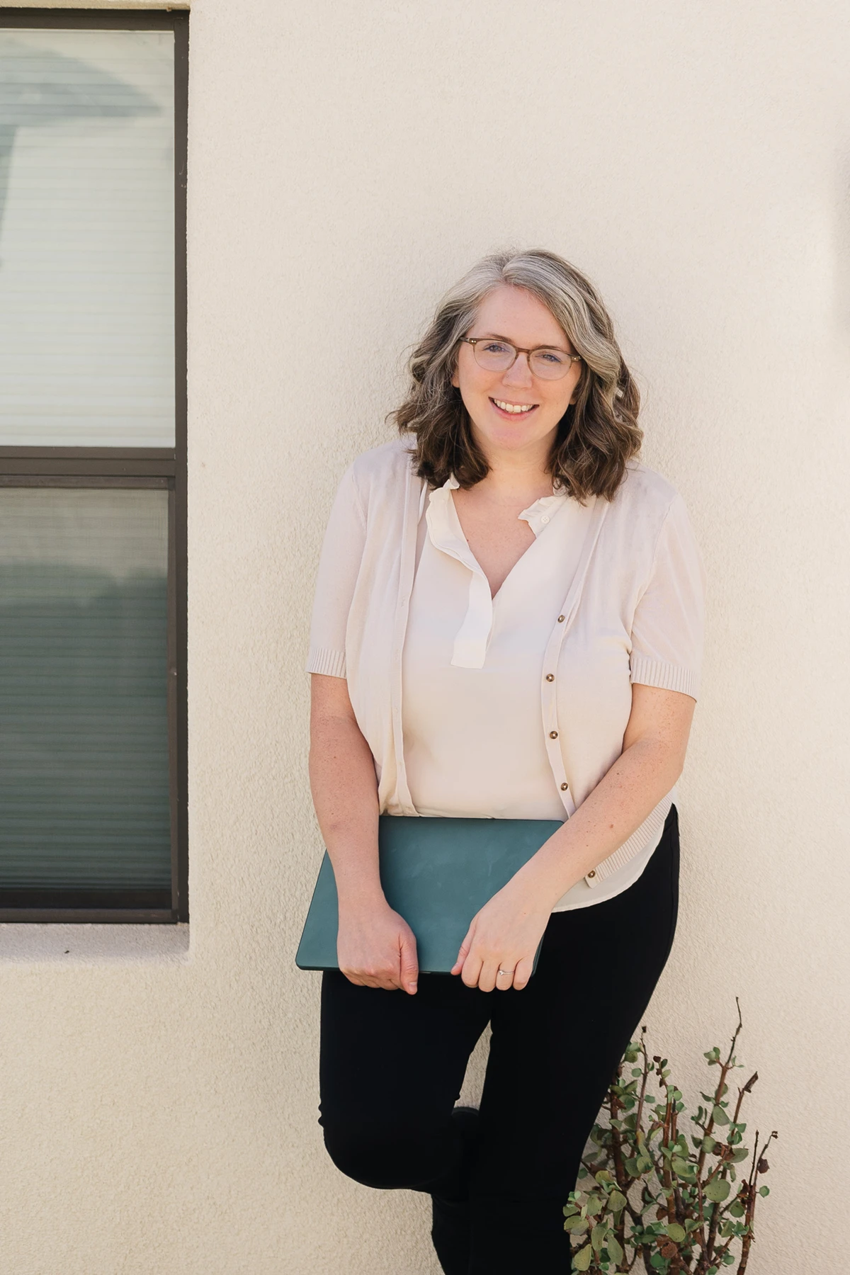 kristin pruis, website designer, holding a laptop, outside an adobe building