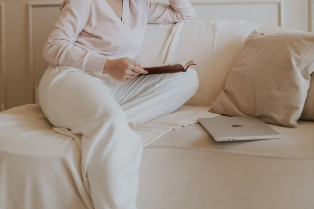woman sitting on a cozy couch reading a book instead of finishing her website